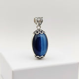 Blue oval pendant with silver decorative frame on a white background 61.00ct
