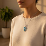 swiss blue topaz round stone 33.75ct Person wearing a necklace with a blue pendant in a warm indoor setting