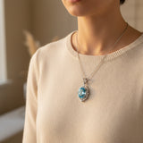 swiss blue topaz round stone 43.70ct Person wearing a necklace with a blue pendant against a neutral background