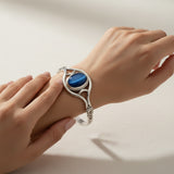 cat eye stone 58.40ct Silver bracelet with a blue stone on a wrist against a neutral background