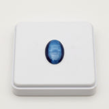 cats eye stone 57.35ct Blue oval gemstone on a white square platform