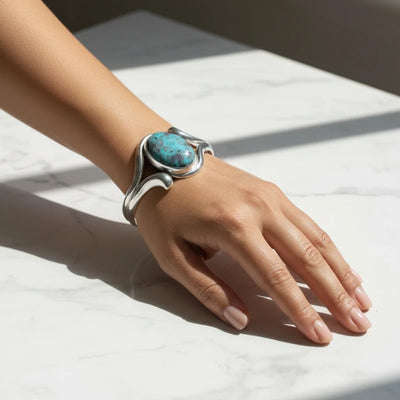 nishapur turquoise 74.90ct Silver bracelet with a turquoise stone on a hand against a white background