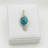 nishapur turquoise 27.29ct pendant with silver wire wrapping on a white cushion