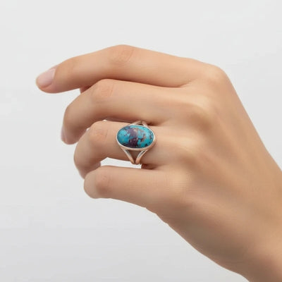 nishapur turquoise 33.90ct Hand wearing a ring with a turquoise stone on a light gray background