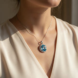 swiss blue topaz round stone 29.05ct Necklace with a blue gemstone pendant worn by a person in a beige top.