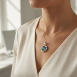 swiss blue topaz round stone 29.50ct  Necklace with a blue gemstone pendant worn by a person in a cream outfit.