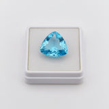 swiss blue topaz trillion 31.60ct Trillion shaped blue gemstone in a white display box on a light gray background
