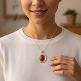 natural red agate carnelian aqeeq 33.65ct Woman wearing a necklace with a red pendant, indoors.