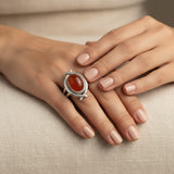 natural red agate carnelian aqeeq 37.10ct Silver ring with a red stone on a hand against a beige background