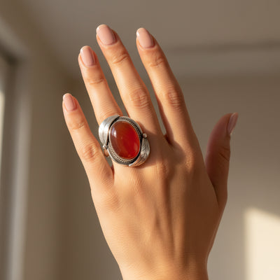 natural red agate carnelian aqeeq 28.00ct Hand wearing a silver ring with a red stone against a neutral background